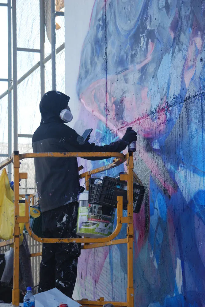 Graffitero pintando el mural