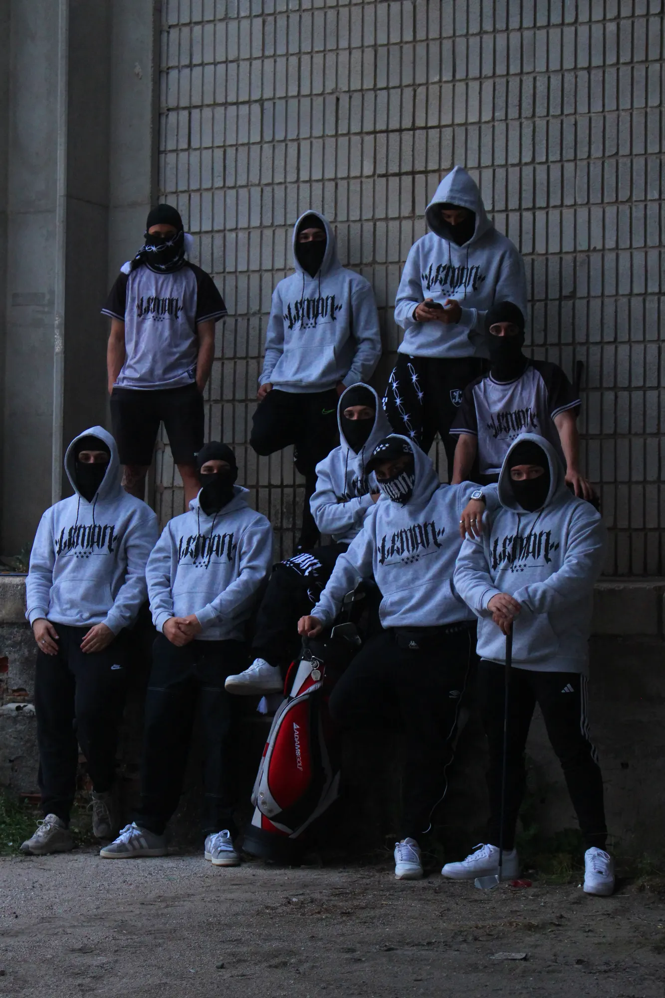 Grupo con sudaderas Lemon Wear grises junto a una pared