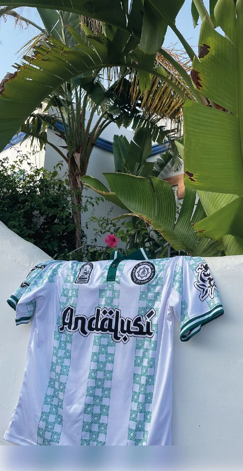 Camiseta Andalusí blanca y verde colgada entre palmeras