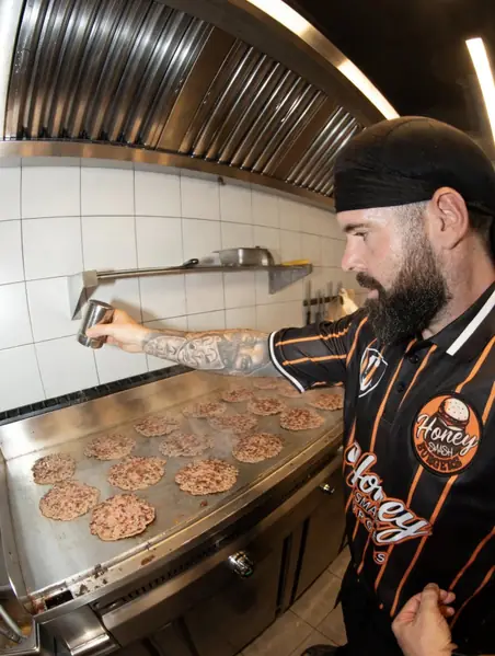 Cocinero de Honey Smash Burgers en la plancha